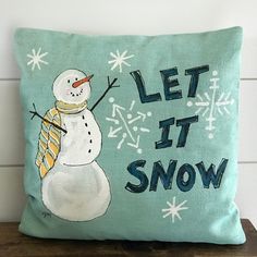 a pillow with a snowman on it that says let it snow