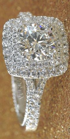 a diamond ring sitting on top of a gold glitter covered surface with diamonds surrounding it