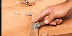 a man is working on a piece of wood with a pair of pliers in his hand