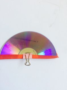 a cd with a red band around it on a white surface and a metal hook