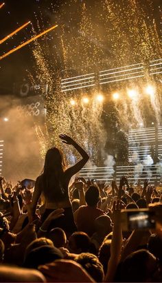 a woman standing on top of a stage surrounded by confetti and fireworks in the air