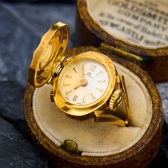 This vintage Bucherer fold top watch ring dates from around the 1920's. The ring is crafted in naturally patinated 18k yellow gold. The watch currently keeps at least 2 hours of time, however, the ring is more meant for fashion as opposed to time-keeping. We are not able to offer a warranty on the movement.  The hallmarks from Switzerland that indicate it was made between 1917 and 1934. Victorian Yellow Gold Self-winding Watch, Vintage Formal Watches With Rotating Bezel, Antique Yellow Gold Self-winding Watch, Antique Self-winding Yellow Gold Watch, Victorian Yellow Gold Watches For Anniversary, Vintage Rings With Rotating Bezel For Anniversary, Victorian Yellow Gold Anniversary Watch, Vintage Anniversary Rings With Rotating Bezel, Vintage Jewelry With Rotating Bezel For Formal Occasions