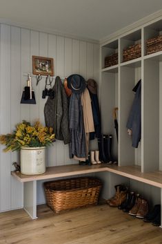 a coat rack with hats, boots and umbrellas hanging on the wall above it