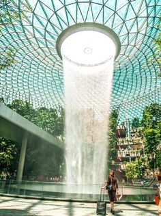 air hostess standing in front of the rain vortex at the jewel in Singapore Changi Airport Marina Bay Sands Pool, Cloud Forest, Orchid Garden