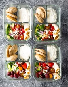 four plastic containers filled with food on top of a gray surface and some breads