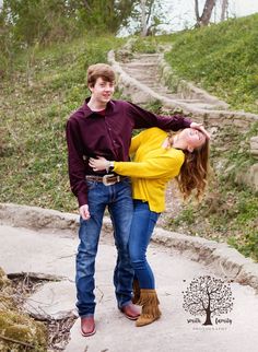 a young man and woman are posing for a photo on a path in the woods