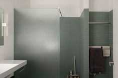 a bathroom with green tile walls and white counter tops, along with a shower stall