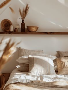 a bed with white linens and pillows on top of it next to a wooden shelf