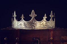 a silver crown sitting on top of a wooden trunk in front of a black background