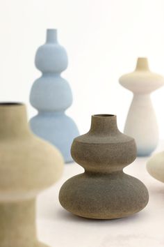 several different colored vases sitting on top of a white countertop next to each other