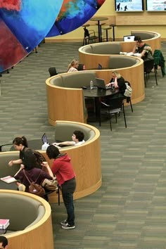 several people sitting at tables with laptops and umbrellas in the middle of them