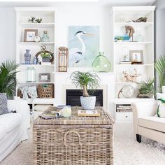 a living room filled with white furniture and lots of plants on top of shelves next to a fire place