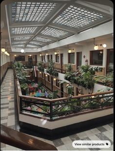 an indoor atrium with plants and potted plants on the balconies in front of windows