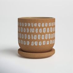 a brown cup with white designs on it