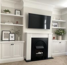 a living room with white bookcases and a flat screen tv mounted on the wall