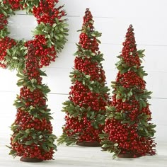 three small christmas trees with red berries on them