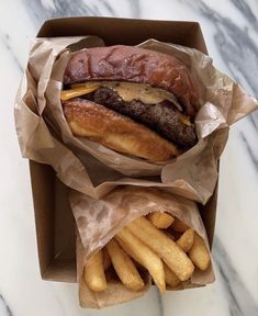 a hamburger and french fries in a box on a marble counter top with a marble background