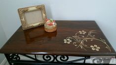 a wooden table with a small vase on it and a photo frame next to it