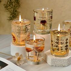 four candles sitting on top of a table next to an open book and some flowers