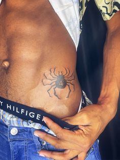 a man with a spider tattoo on his stomach holding onto a black belt that says my hilfiger