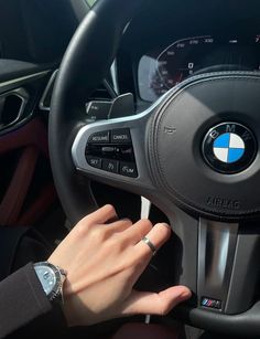 a woman's hand on the steering wheel of a bmw car, while she is driving