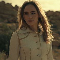 a woman standing in the desert wearing a white coat