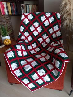 a crocheted blanket sitting on top of a chair in front of a book shelf