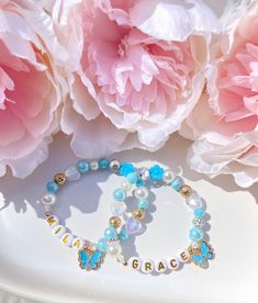 two bracelets sitting on top of a white plate next to pink peonies