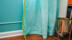 a blue shower curtain next to a gold trash can in a room with hardwood floors