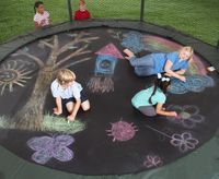 three children sitting on a trampoline with chalk drawings