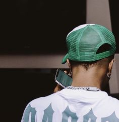 a man with a green hat on his head is looking at something in the distance