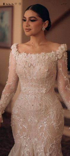 a woman in a wedding dress with long sleeves and an embellishment on her face