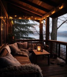 a porch with lights strung from the ceiling and pillows on the couches in front of it