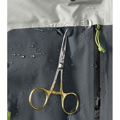 there is a pair of scissors hanging on the side of a jacket with water drops