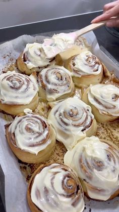 a tray filled with cinnamon rolls covered in icing