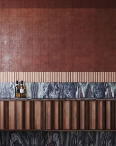 two bottles are sitting on top of the counter next to each other in front of a tiled wall