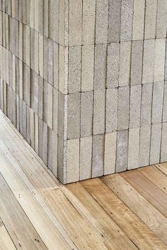 a wooden floor next to a wall made out of concrete blocks and wood planks