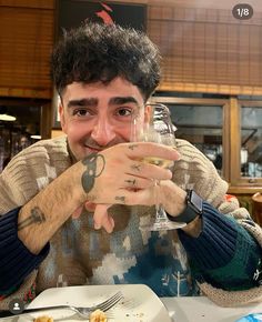 a man sitting at a table with a glass of wine in front of his face