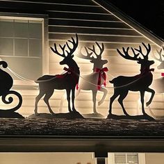 lighted reindeers and sleighs on the roof of a house at night