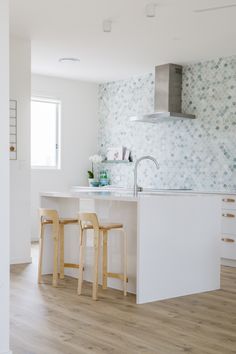 a kitchen with two stools next to an island and a stove top oven in it