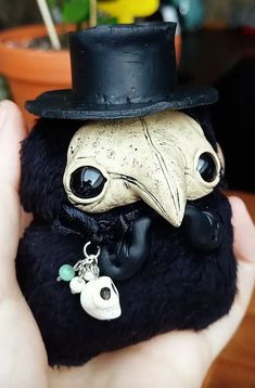 a hand holding a small stuffed animal with a top hat on it's head