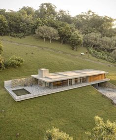 an aerial view of a house in the middle of a grassy field with trees around it