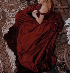 an old fashion photo of a woman in a brown dress sitting on the floor with her hands behind her back