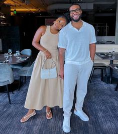 a man and woman standing next to each other in front of a dining room table