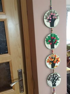 four paper plates hanging on the wall in front of a door with flowers painted on them