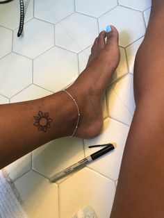 a person with a tattoo on their leg sitting on the floor next to a pen