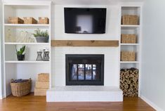 a living room with white shelves and a flat screen tv above the fireplace