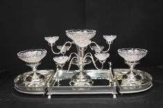 a silver tray with five glass bowls on it and four candlesticks in the middle