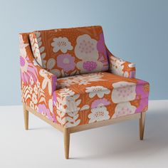 an orange and pink flowered chair on a white floor with blue wall in the background