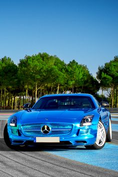 a blue sports car driving on a race track with trees in the backgroud